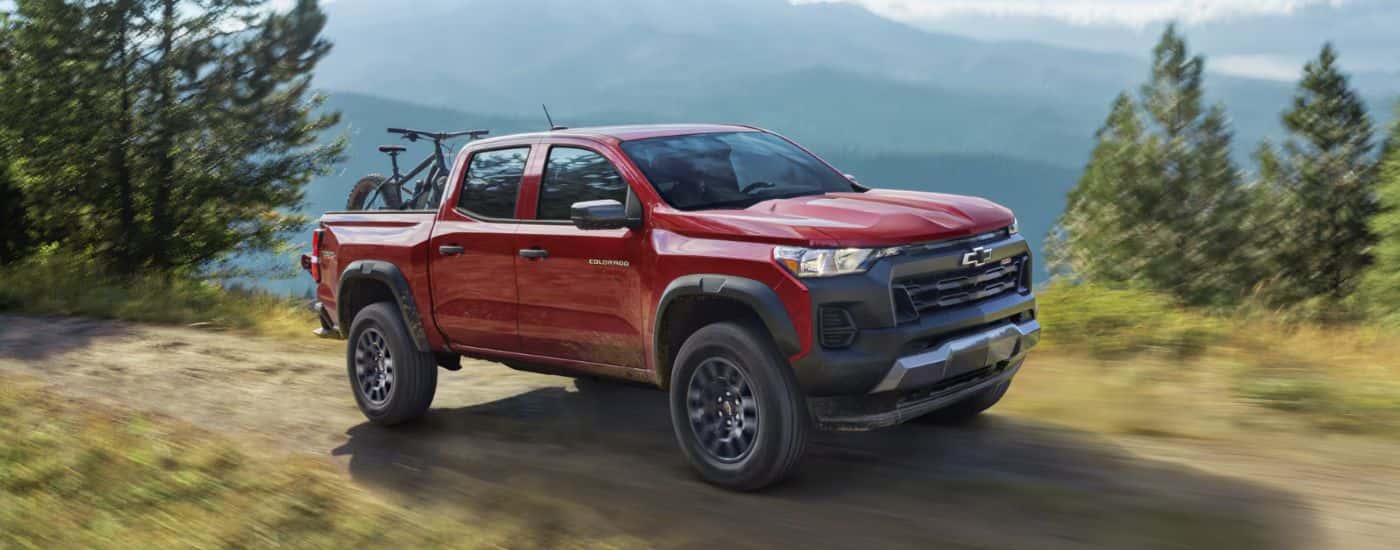 Red 2026 Chevy Colorado on a dirt road with a bike in the back.