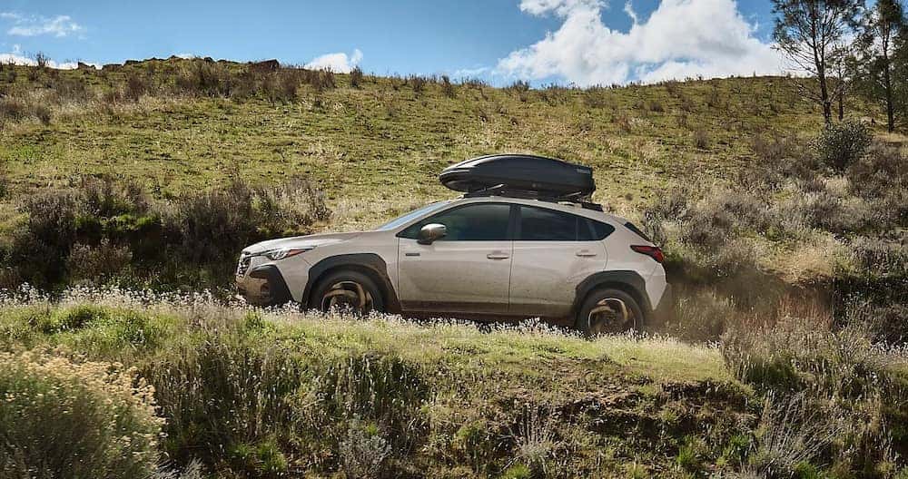 A beige 2026 Subaru Crosstrek SUV driving along a dirt road