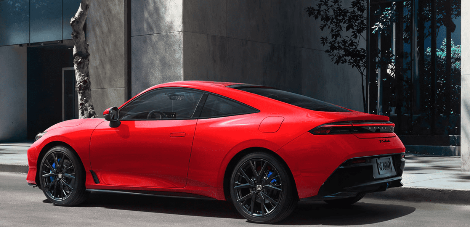 A red, new 2026 Honda Prelude sits parked on a city street.