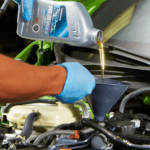 A close-up of a service technician performing an oil change on a vehicle in the service center.