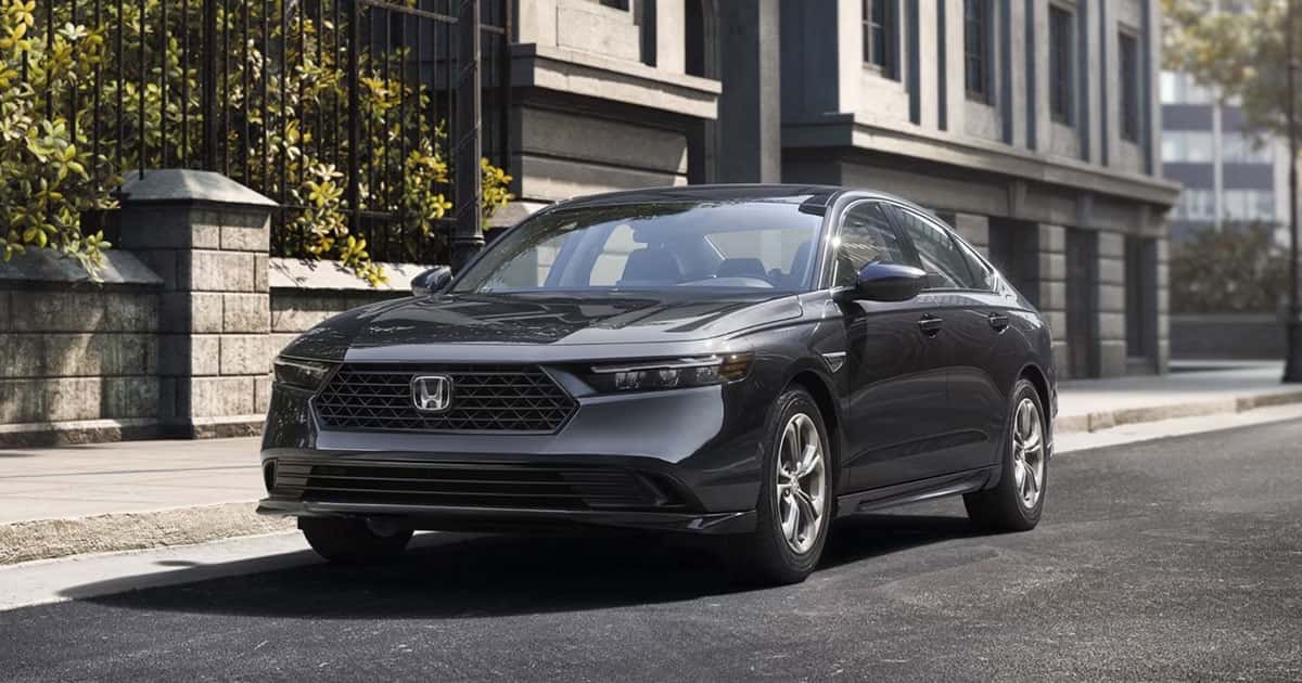 A dark grey 2026 Honda Accord parked in front of a row of townhouses.