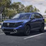 A blue Honda CR-V parked by a soccer field.