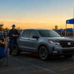 The Honda Ridgeline, featuring a crew cab layout and a tailgate party setup in a parking lot.