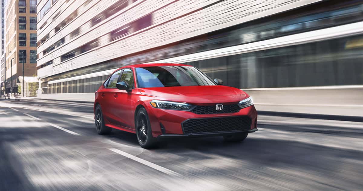 A red Honda Civic driving through a city street.