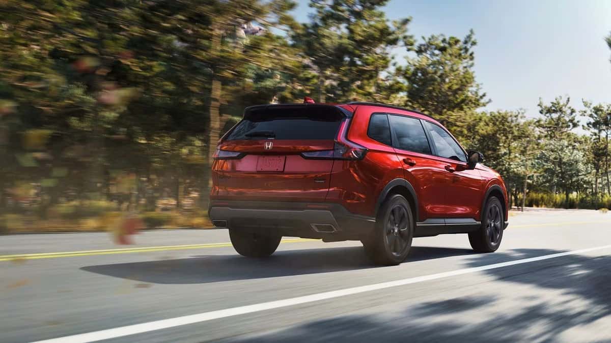 2026 Honda CR-V hybrid rear three-quarter view driving a tree-lined road