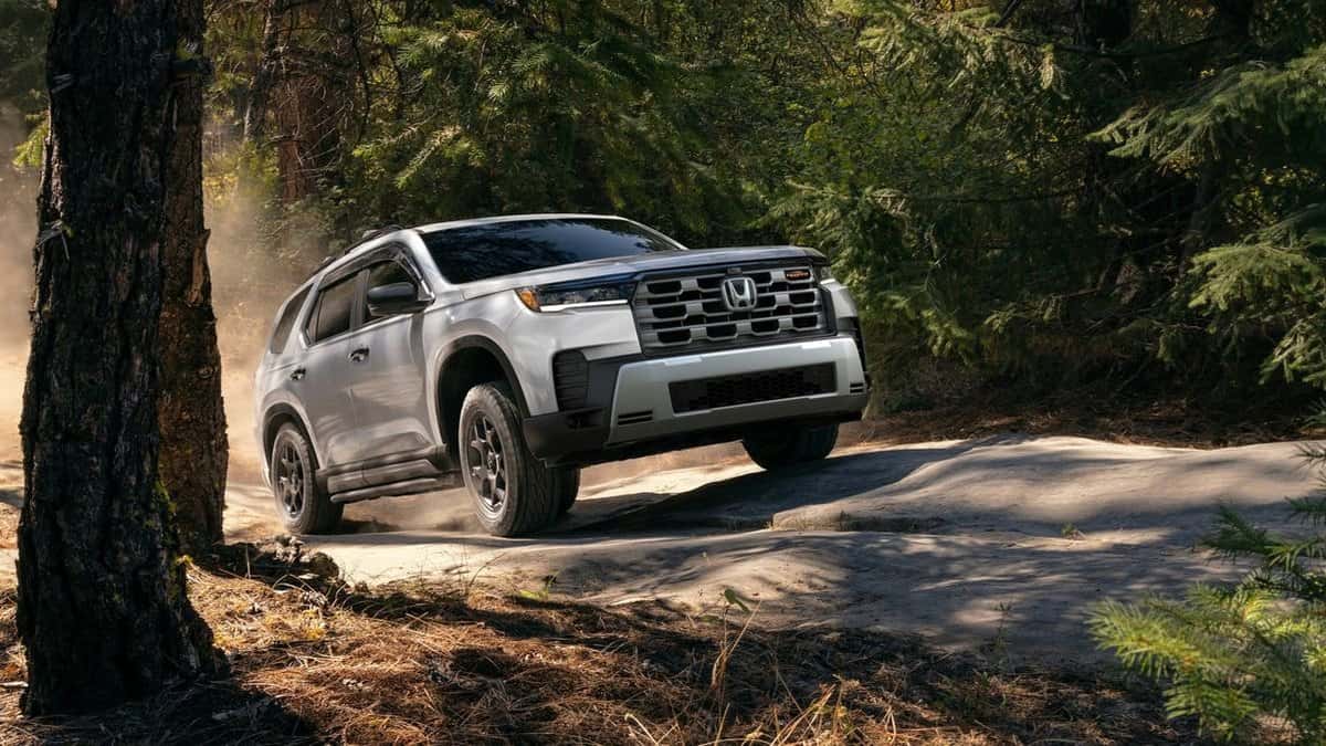 2026 Honda Pilot TrailSport in Solar Silver Metallic on a forest trail with all-terrain tires