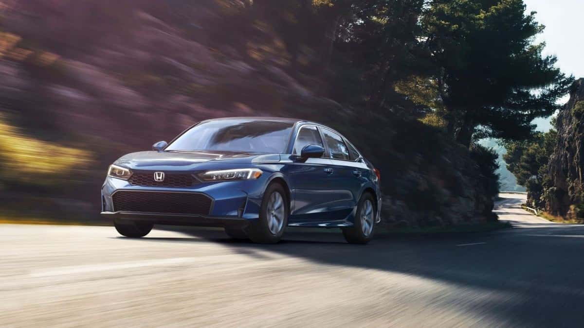 2026 Honda Civic LX sedan in Blue Lagoon Pearl on a wooded road