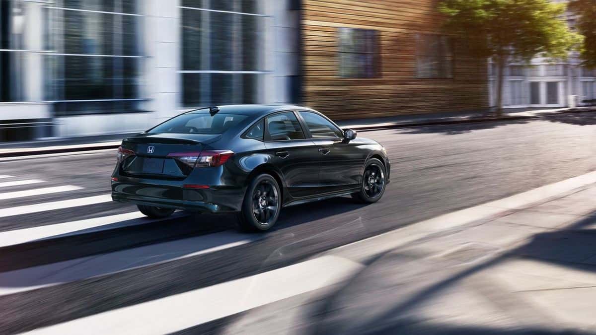 2026 Honda Civic Sport Hybrid sedan in Crystal Black Pearl driving at night