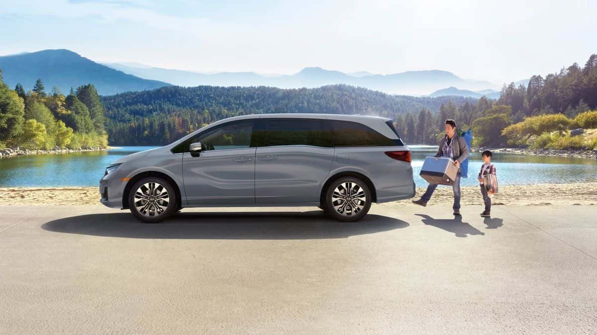 2026 Honda Odyssey parked lakeside while a father and son unload camping gear