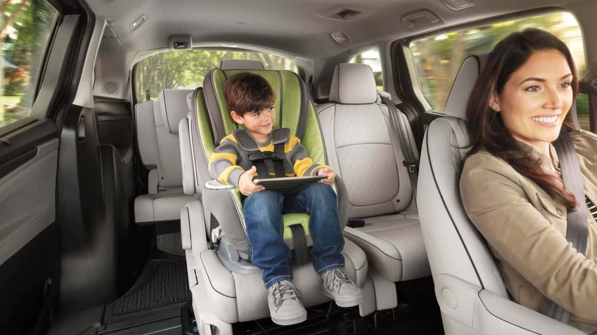 Child secured in a car seat in the second row of a 2026 Honda Odyssey EX-L, Magic Slide seat shifted to open a walk-through aisle