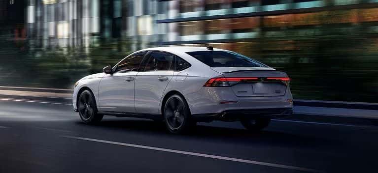 2026 Honda Accord Sport Hybrid in Platinum White Pearl driving through the city at dusk
