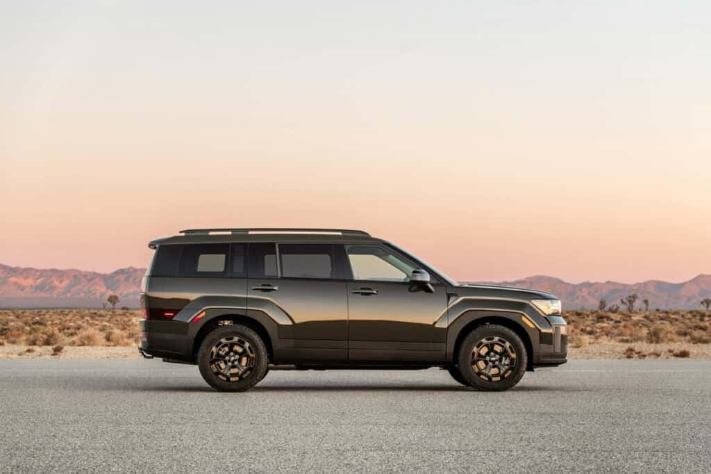The right side view of the Hyundai SANTA FE XRT stopped with the mountains under the sunset in the background.