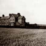Grayscale Photo of House on Grass Field