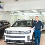 A Huffines car salesman posing next to a Hyundai Santa Fe