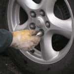 gloved hand changing lug nuts on a tire