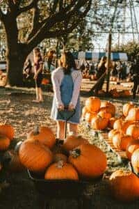 a woman carrying a bunch of pumpkins in a trailer