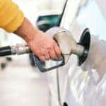 man putting gas pump into white car