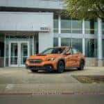 An orange Subaru WRX parked in front of Huffines Subaru Corinth