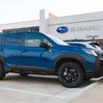 A blue Subaru Forester Wilderness parked in front of Huffines Subaru Corinth