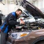 A mechanic inspects the engine of a Subaru at Huffines Subaru Service Center