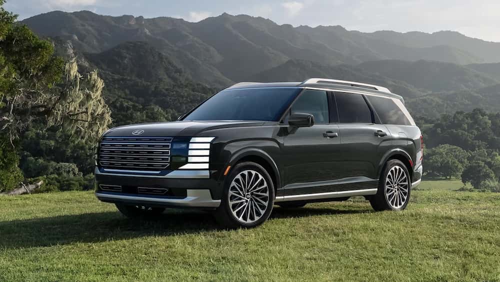 A black 2026 Hyundai Palisade SUV with green mountains in the background