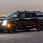 A black 2027 Hyundai Palisade Hybrid SUV with its headlights on at dusk