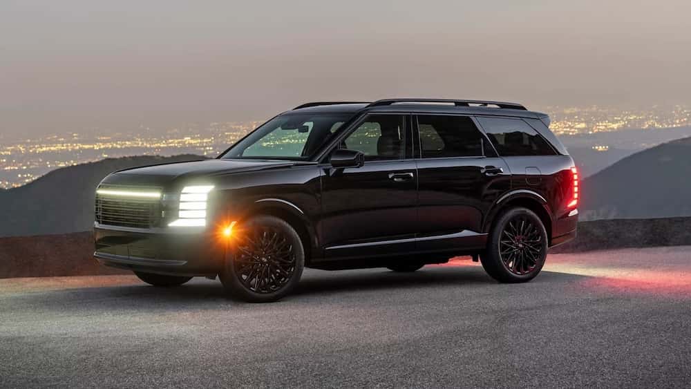 A black 2027 Hyundai Palisade Hybrid SUV with its headlights on at dusk