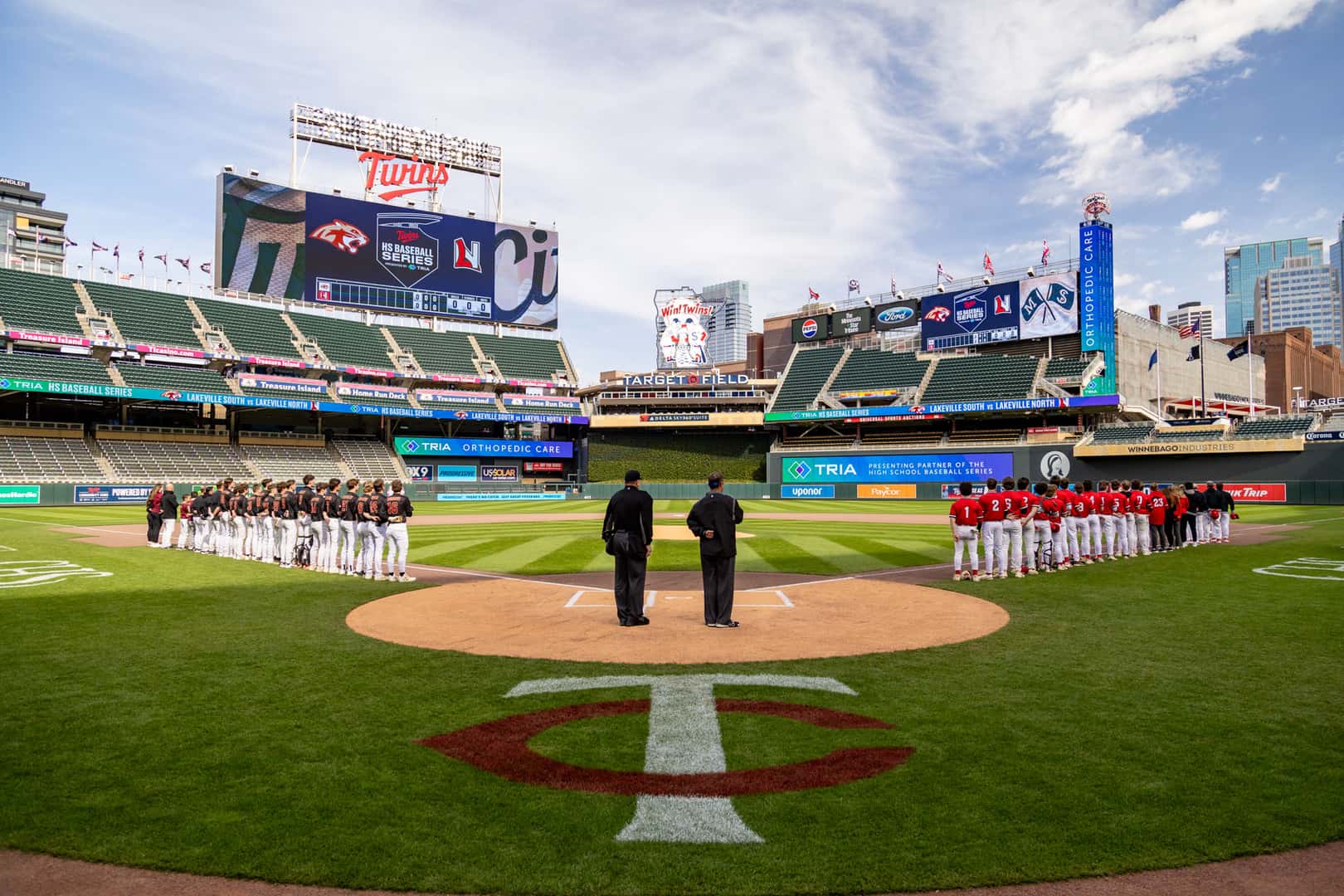 Lakeville North and Lakeville South line up along the baselines at Target Field for the national anthem