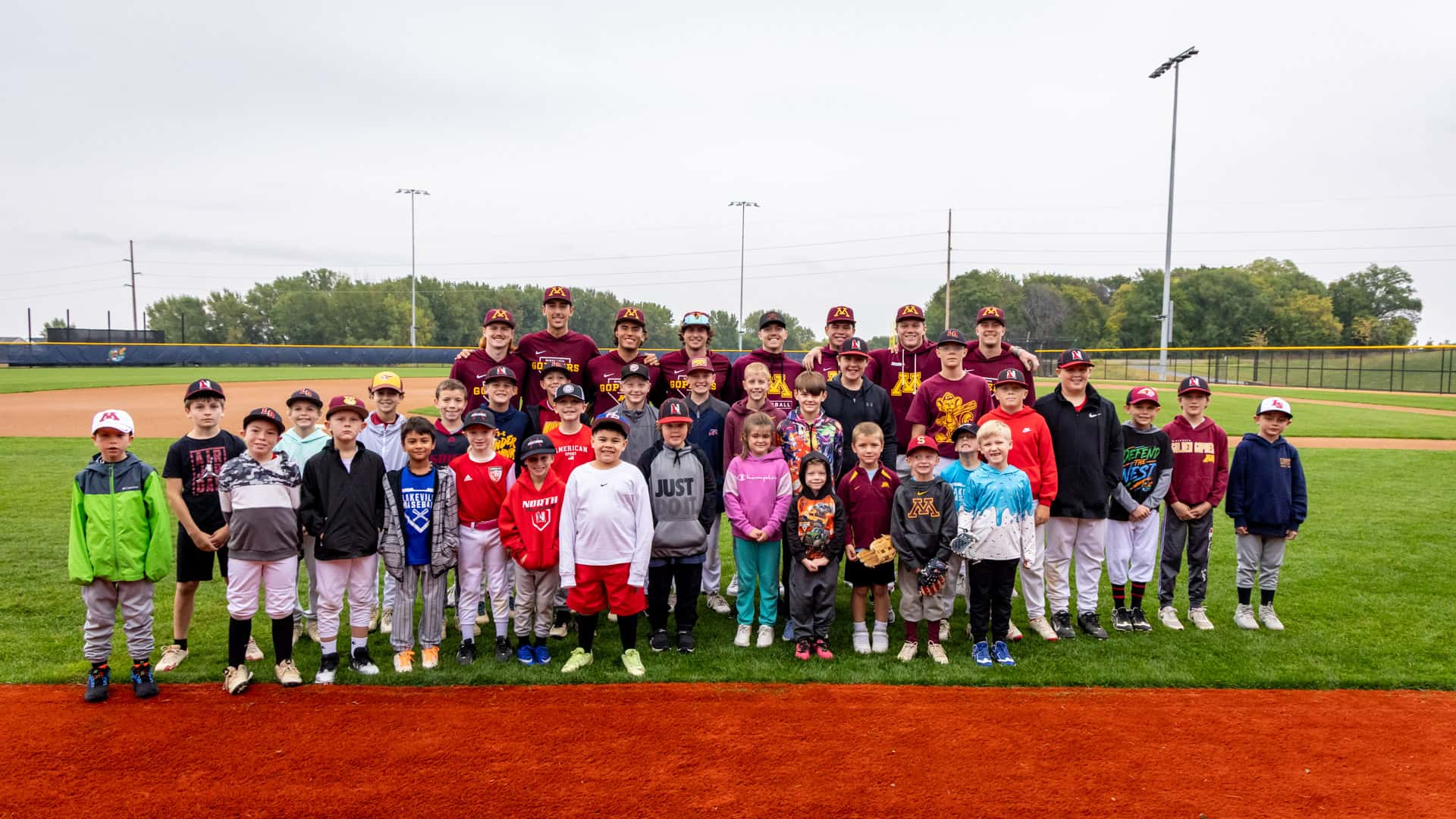 Young players and Gopher Baseball instructors gathered for a group photo after the youth clinic at Belzer Stadium
