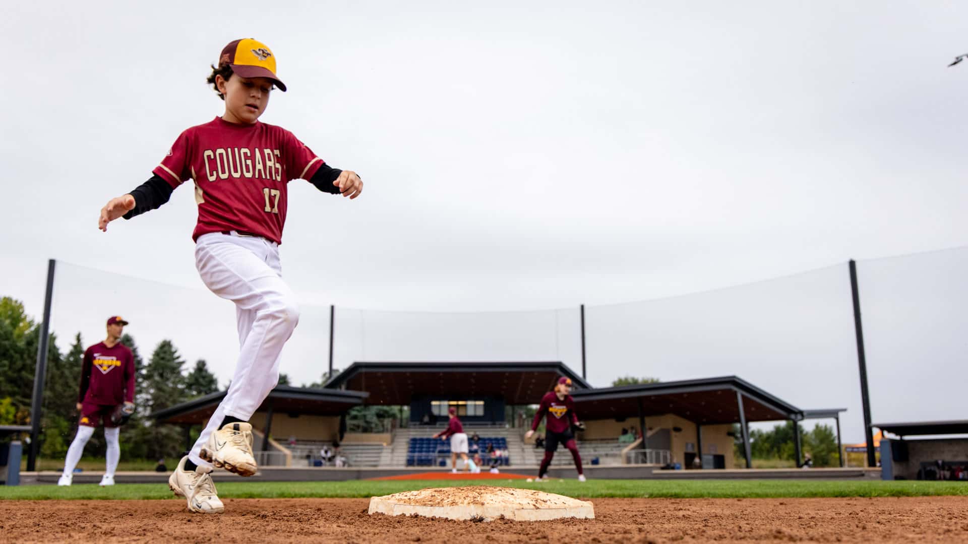 Youth baseball camper rounding second base during a baserunning drill at Belzer Stadium