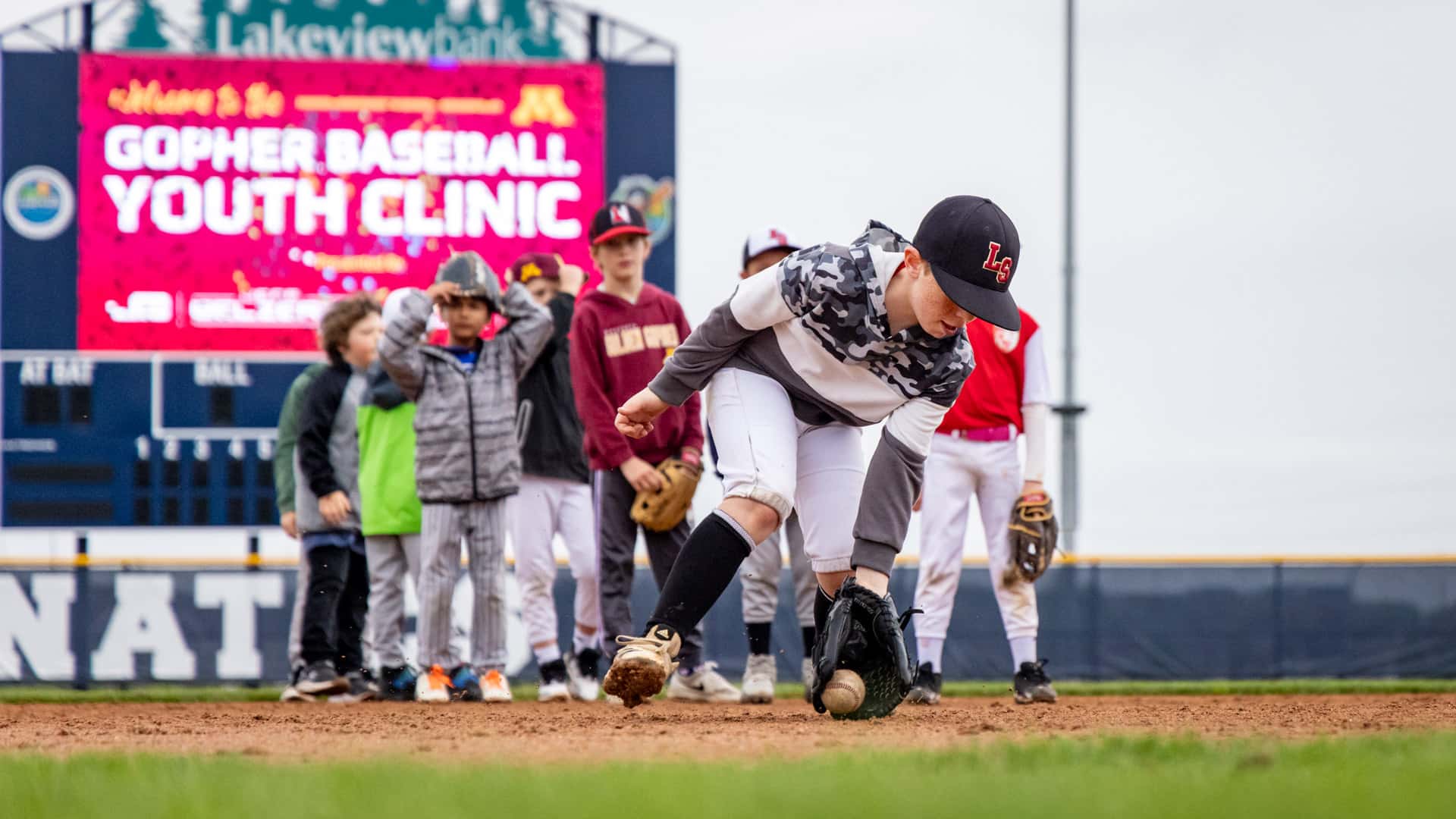 Young baseball player fielding a ground ball during infield training at Belzer Stadium