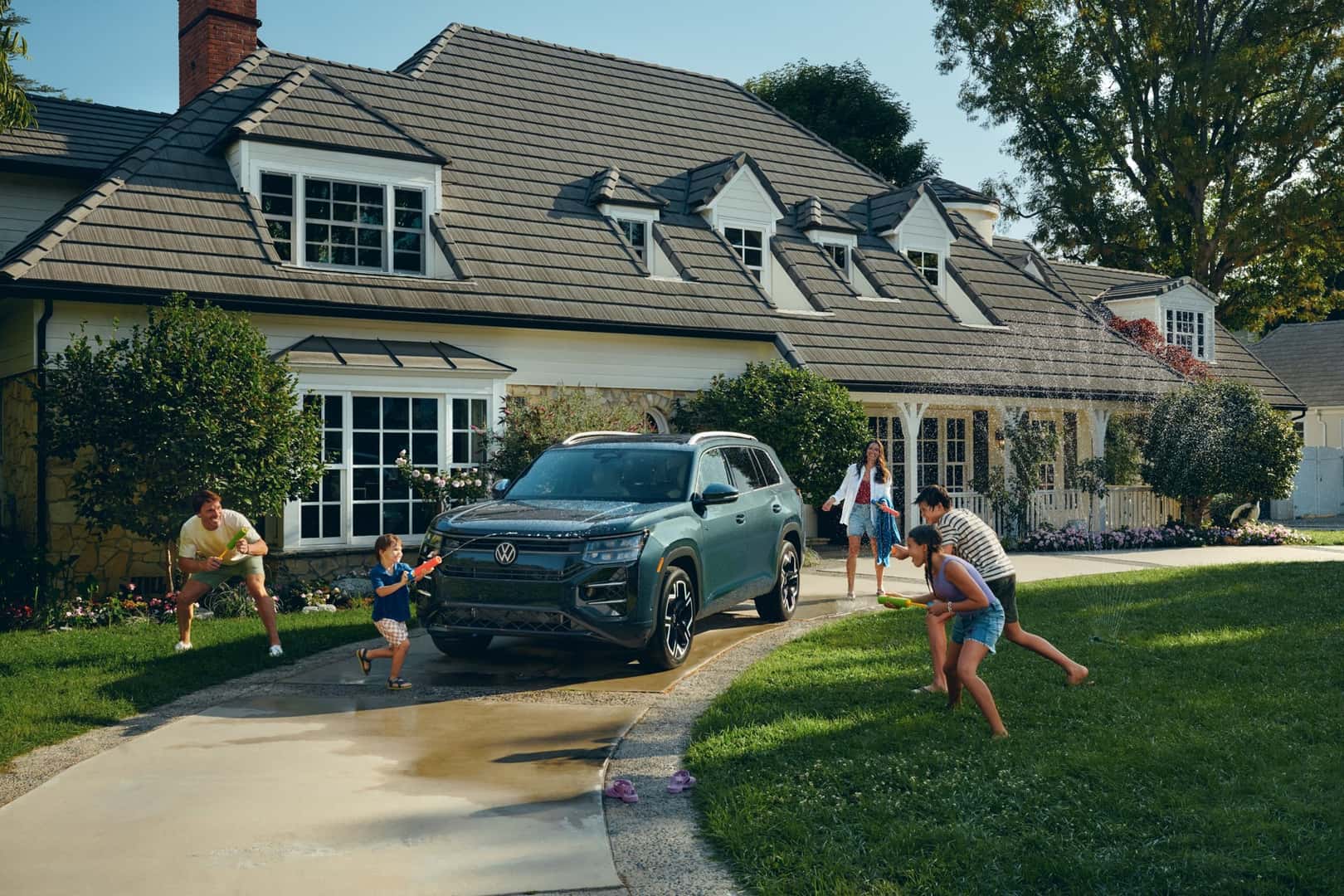 2027 Volkswagen Atlas SEL R-Line parked in a driveway while a family plays with water guns