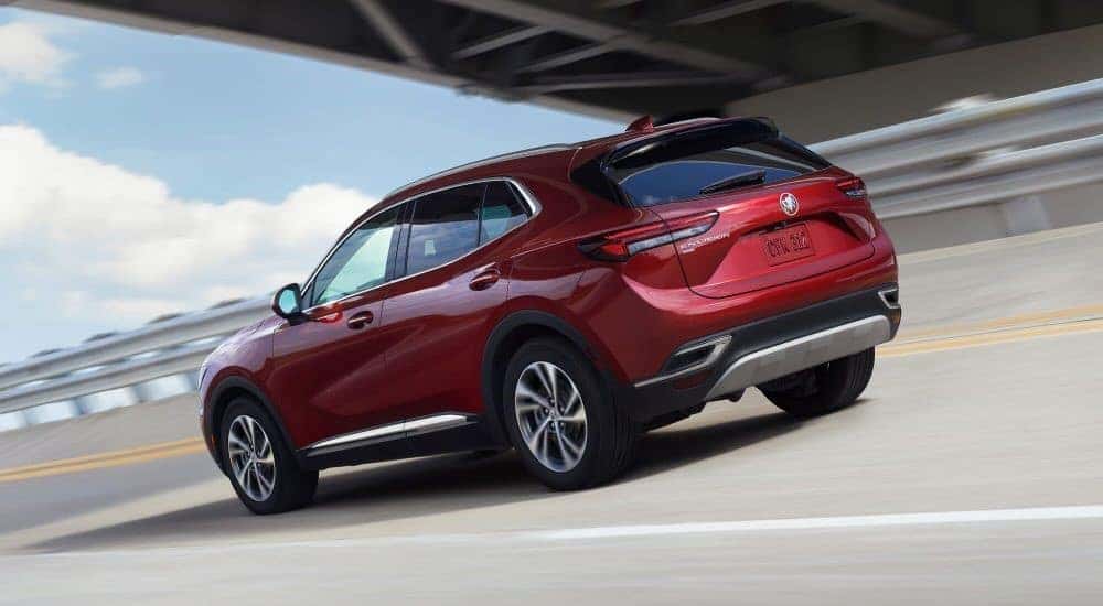 A red 2023 Buick Envision is shown from the rear driving under a bridge.