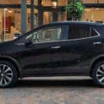 A black 2022 Buick Encore is shown parked near a shop.