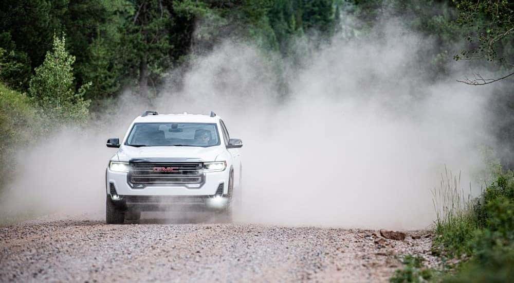 A white 2020 GMC Acadia AT4 is shown kicking up dust.