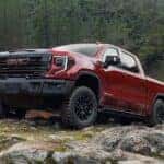 One of the more popular lifted trucks for sale, a red 2023 GMC Sierra 1500 AT4X, is shown parked off-road.