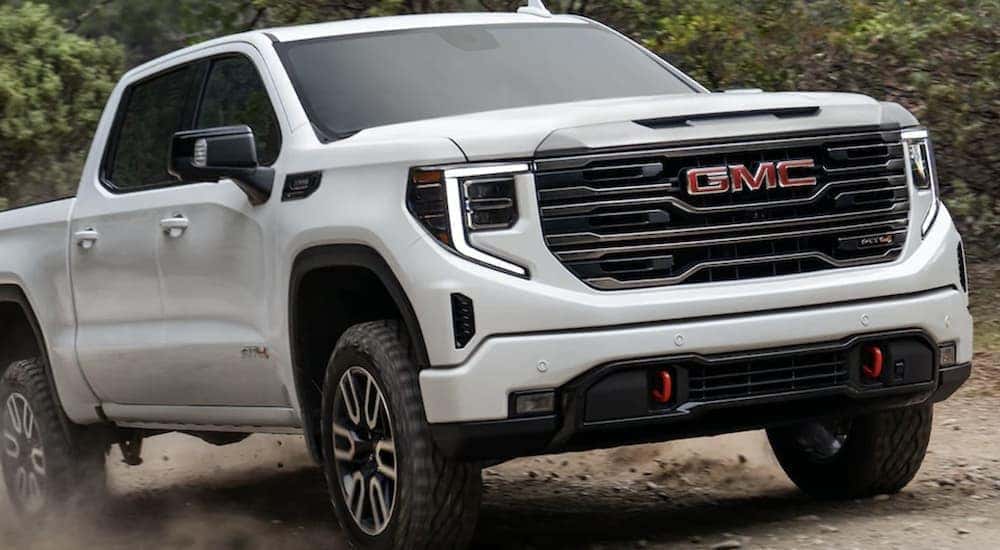 A white 2023 GMC Sierra 2500 HD AT4 is shown driving.