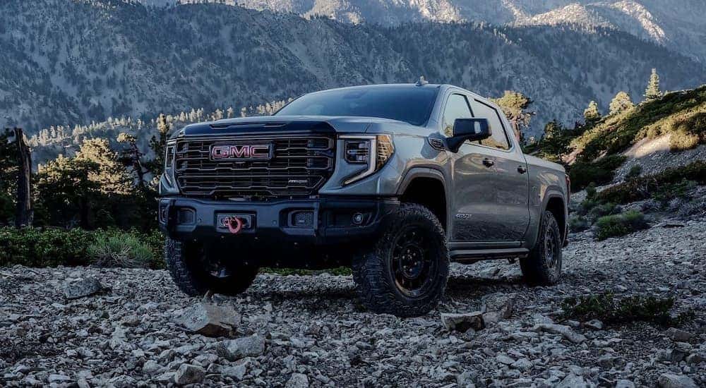 A grey 2024 GMC Sierra 1500 is shown parked off-road in the mountains.