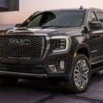 A black 2024 GMC Yukon XL is shown parked on a driveway.