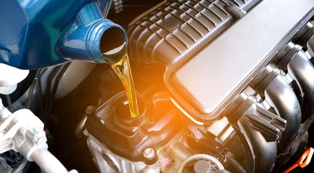 A can of oil is shown being poured into an engine.
