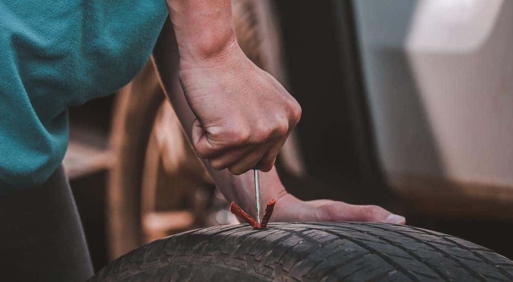 A close-up of a person plugging a tire hole is shown.