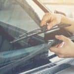 A person is shown fixing wiper blades at a GMC service center.