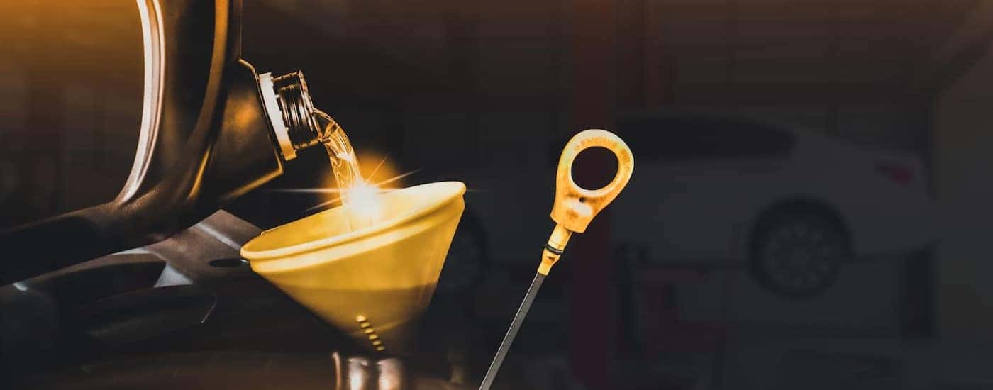 Oil is shown being poured into a funnel near a dipstick.