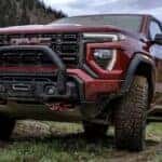 A red 2024 GMC Canyon is shown parked off-road after visiting a dealer with GMC trucks for sale.