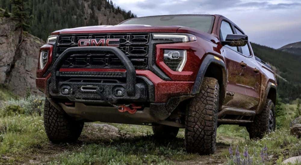A red 2024 GMC Canyon is shown parked off-road after visiting a dealer with GMC trucks for sale.