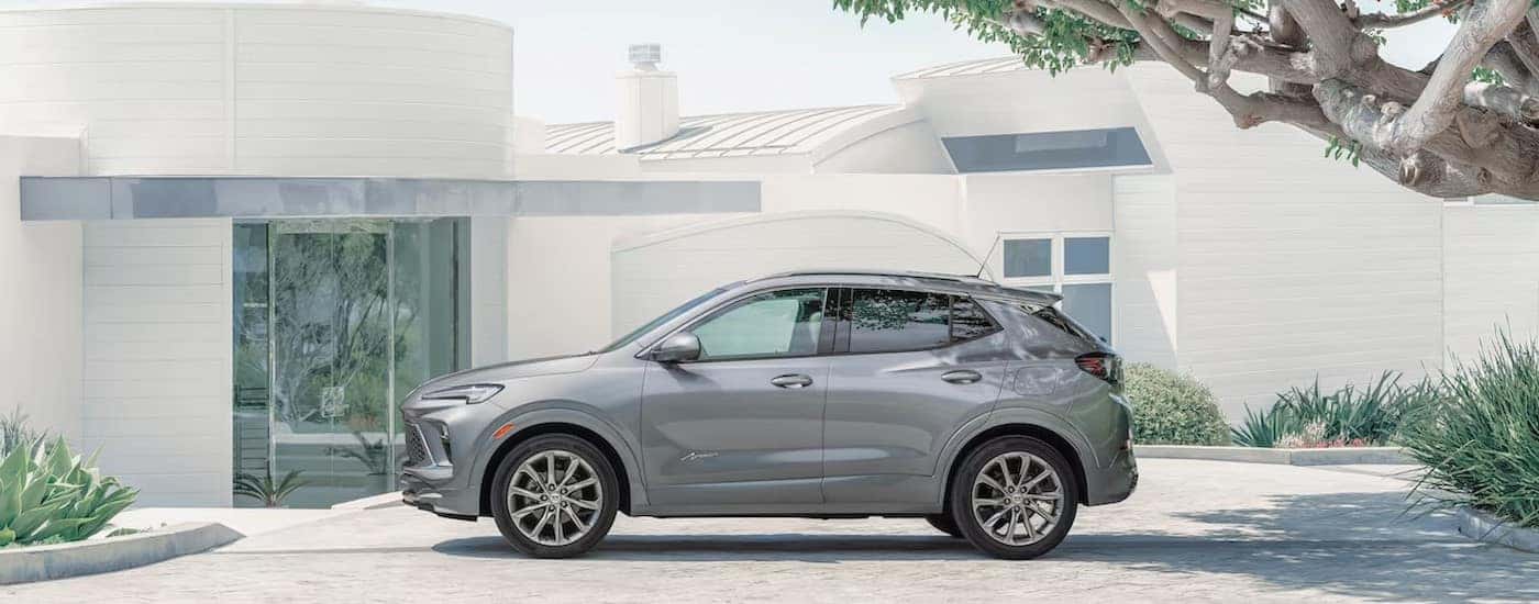 A silver 2024 Buick Encore GX is shown parked near a house.
