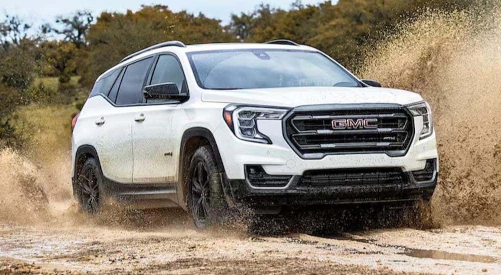 A white 2024 GMC Terrain AT4 is shown driving on mud.