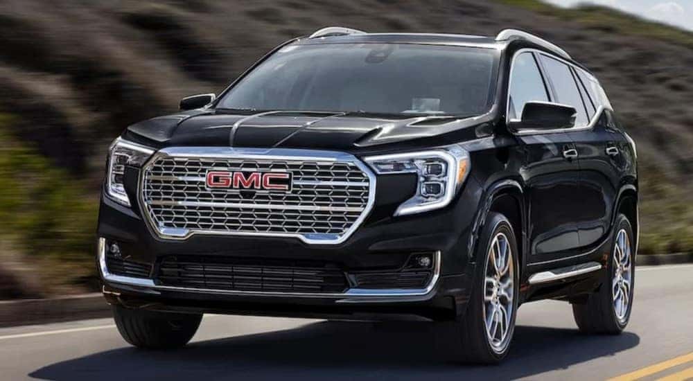 A black 2024 GMC Terrain is shown driving on a highway after visiting a GMC dealer near Kennesaw.