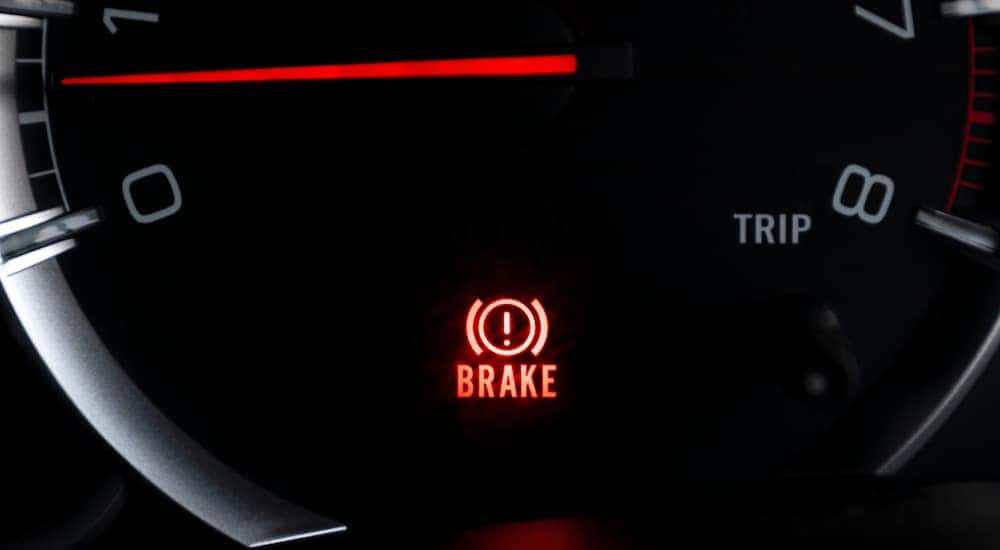The illuminated brake icon on the dashboard of a car getting GMC service near Marietta.