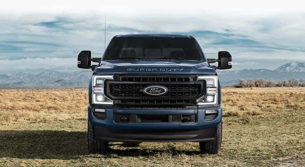 Front angle view of a blue 2021 Ford F-250 Super Duty parked off-road.